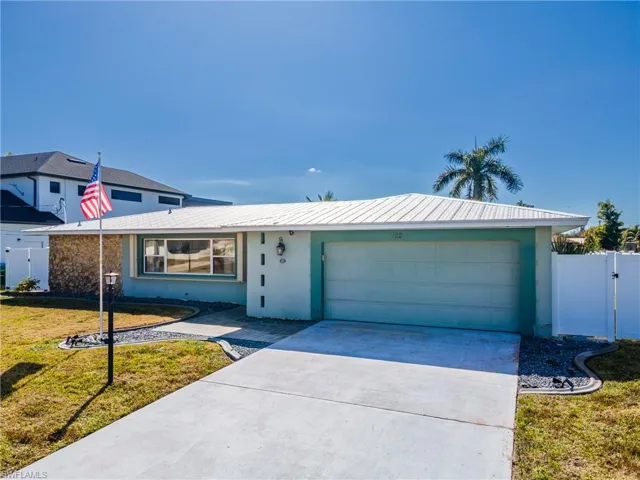 Ranch-style home featuring a gate, stucco siding, driveway, and a metal roof