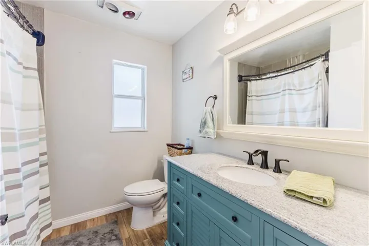 Full bath with vanity, a shower with curtain, and dark wood finished floors
