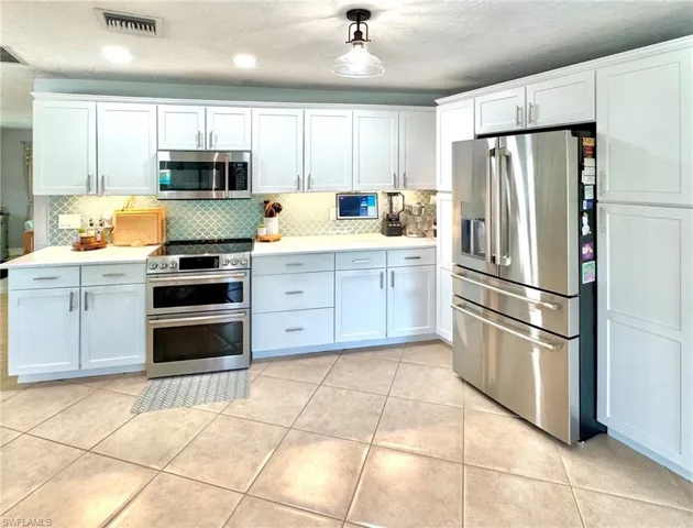 Kitchen featuring white cabinets, stainless steel appliances, and light tile patterned flooring