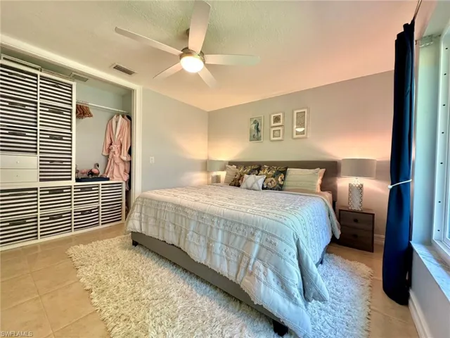 Bedroom with a textured ceiling, a closet, ceiling fan, and light tile patterned flooring