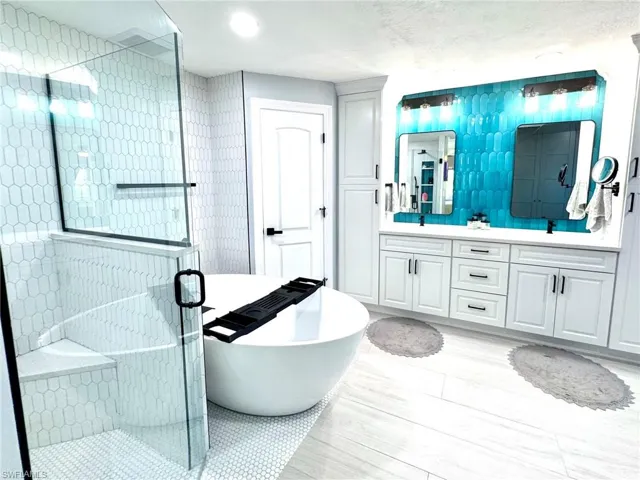 Bathroom with a textured ceiling, vanity, and separate shower and tub