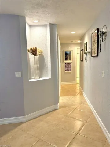 Hall with light tile patterned floors and a textured ceiling