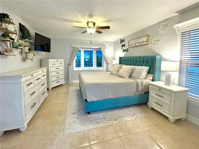 Bedroom featuring multiple windows, a textured ceiling, ceiling fan, and light tile patterned flooring