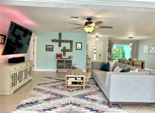 Living room featuring a textured ceiling, ceiling fan, and light tile patterned flooring