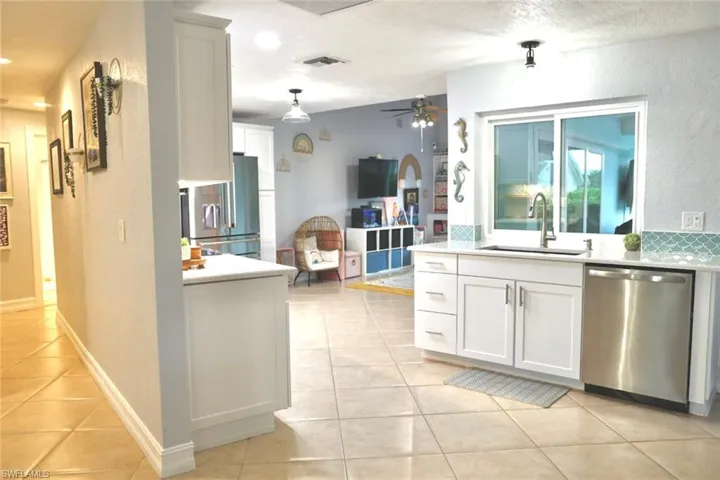 Kitchen featuring white cabinetry, sink, light tile patterned floors, and stainless steel appliances