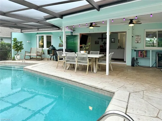 View of swimming pool featuring a patio, ceiling fan, and a lanai