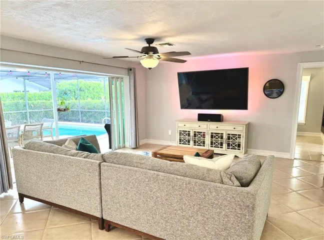 Living room featuring light tile patterned floors, a textured ceiling, and ceiling fan