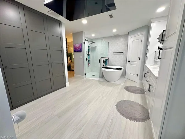 Bathroom with separate shower and tub, hardwood / wood-style floors, and vanity