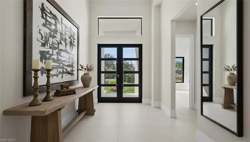 Virtually Staged Doorway to outside featuring tile patterned floors, a towering ceiling, and french doors