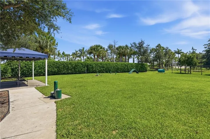 Dog Park 1 of 2 - featuring a shaded pavilion with seating, mature landscaping, paved pathways, and recreational elements for exercise.