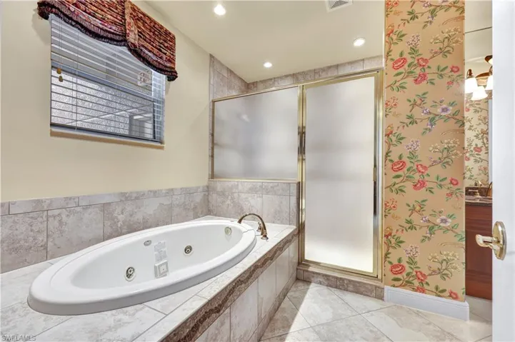 Bathroom featuring a whirlpool tub, a stall shower, vanity, light tile patterned floors, and recessed lighting