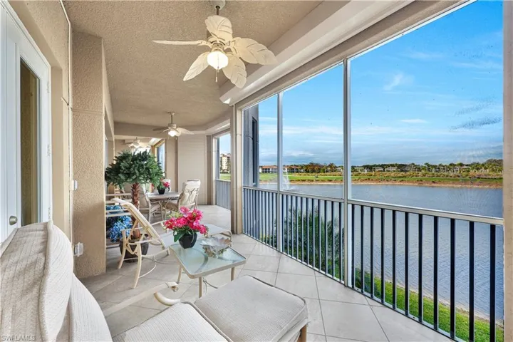 Sunroom with a ceiling fan, a textured ceiling, tile patterned floors, and a water view