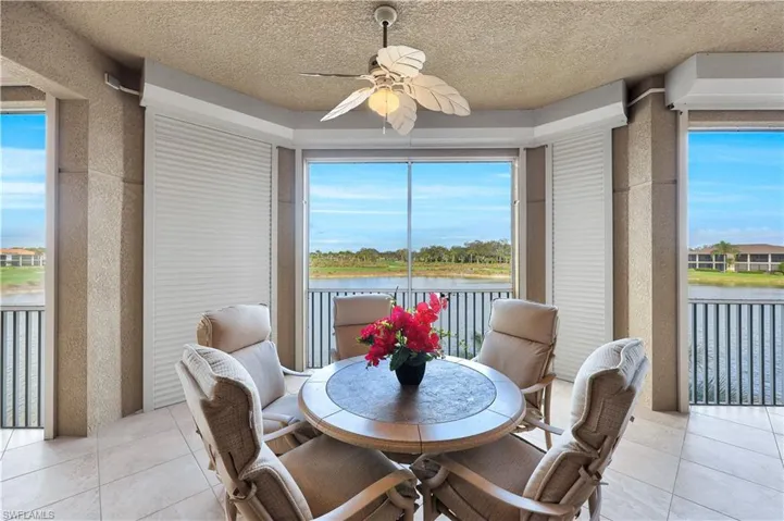 Sunroom / solarium featuring a water view, a textured ceiling, plenty of natural light, and tile patterned floors