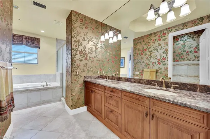Full bathroom with double vanity, a bath, a shower stall, light tile patterned flooring, and wallpapered walls