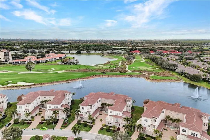 Aerial view of residential area featuring a golf course and a nearby body of water