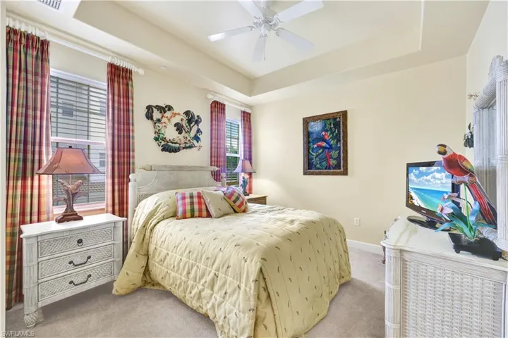 Bedroom featuring a tray ceiling, carpet floors, and ceiling fan