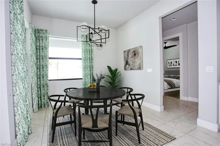 Spacious dining area featuring large format tile flooring, a contemporary chandelier, and a wide window