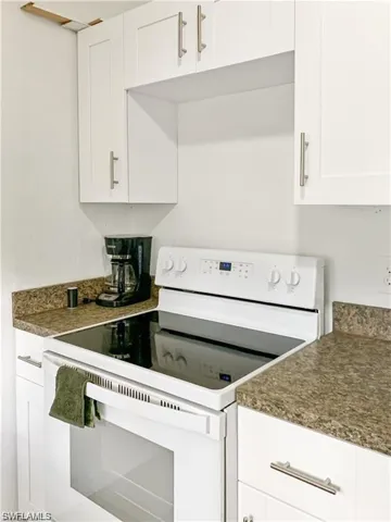 Kitchen featuring white cabinetry and white electric range oven