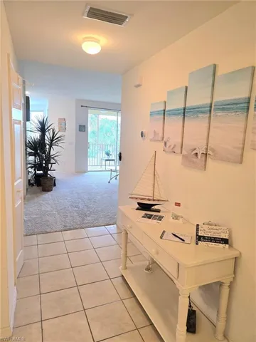Hallway with light carpet and light tile patterned floors