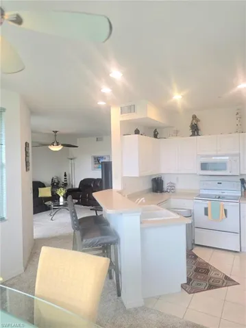 Kitchen with white cabinetry, white appliances, light countertops, recessed lighting, and light tile patterned flooring