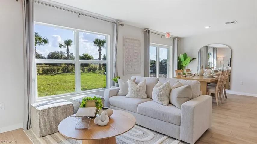 Model home. Living area featuring light wood-style floors and recessed lighting
