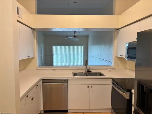 Kitchen with light countertops, stainless steel appliances, white cabinets, a ceiling fan, and pendant lighting