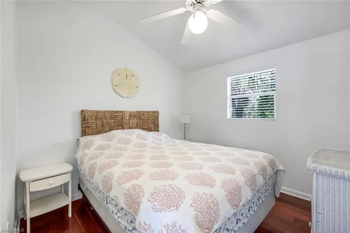 Bedroom with vaulted ceiling, dark wood-style flooring, and ceiling fan