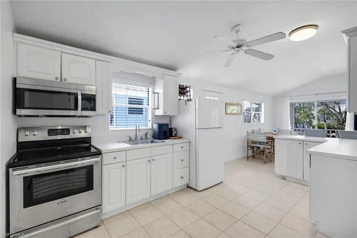 Kitchen with stainless steel appliances, lofted ceiling, light countertops, a ceiling fan, and white cabinets