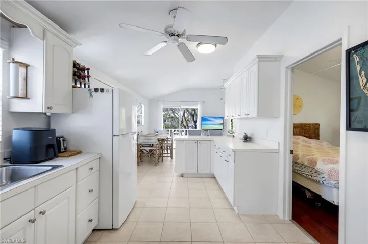 Kitchen featuring light countertops, white cabinetry, vaulted ceiling, a peninsula, and ceiling fan