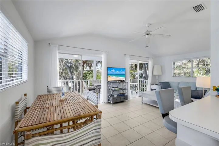 Dining space with a ceiling fan, vaulted ceiling, and light tile patterned floors