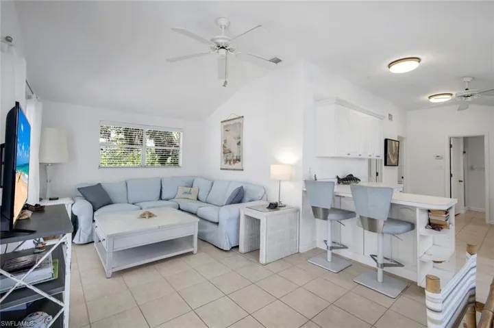 Living room with a ceiling fan, lofted ceiling, and light tile patterned floors