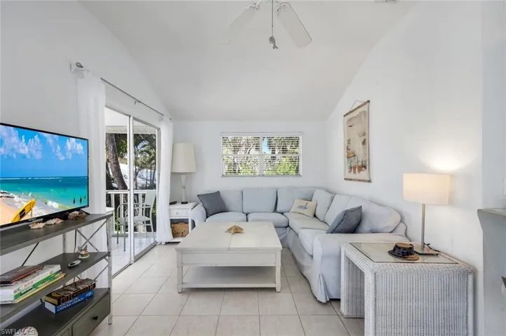 Living area with ceiling fan, vaulted ceiling, and light tile patterned flooring