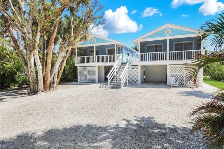 View of front of house with gravel driveway, an attached garage, and a sunroom