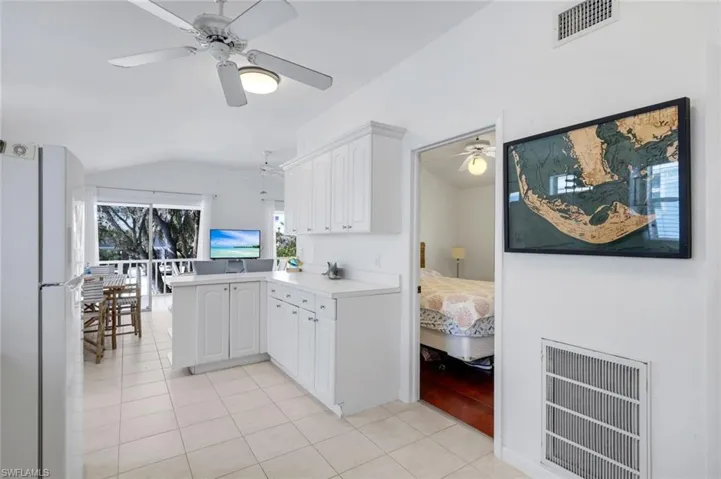 Kitchen with freestanding refrigerator, light countertops, a peninsula, white cabinetry, and light tile patterned floors
