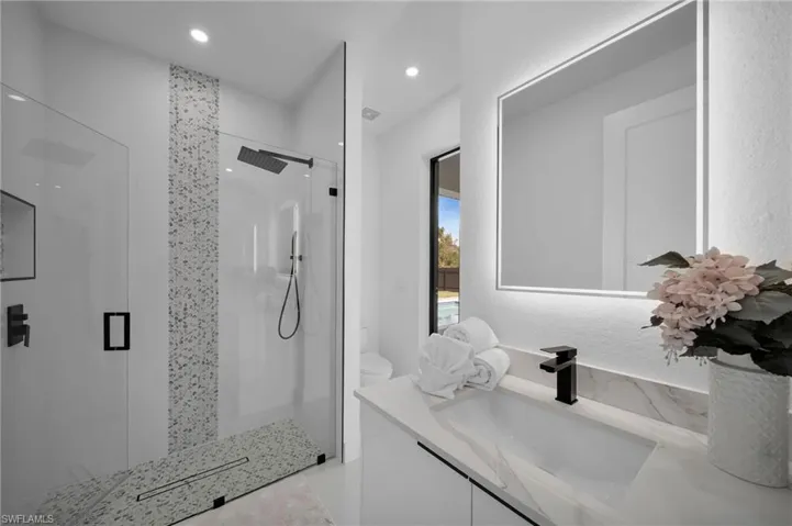 Bathroom featuring a shower stall, toilet, vanity, and recessed lighting