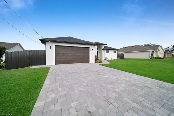 View of front of home with a garage, decorative driveway, and stucco siding