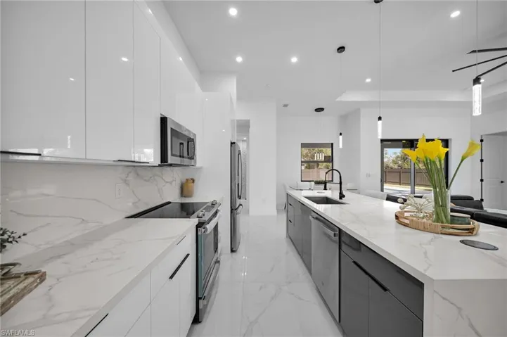 Kitchen featuring modern cabinets, appliances with stainless steel finishes, a sink, white cabinets, and recessed lighting
