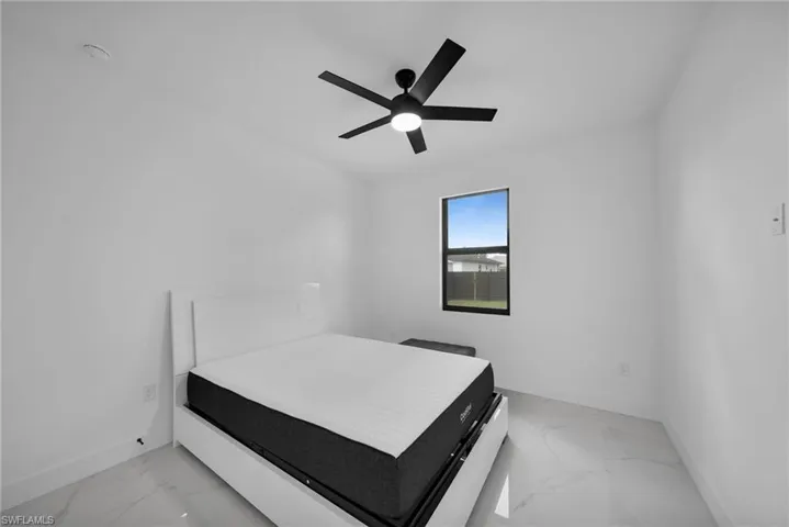 Bedroom with light marble finish flooring, baseboards, and a ceiling fan
