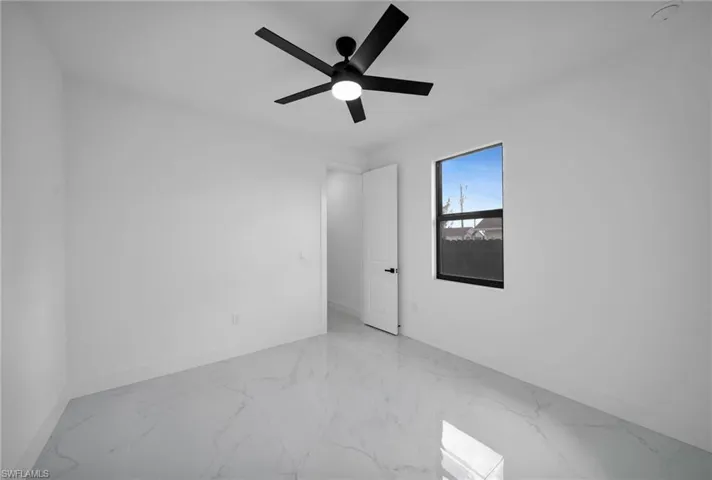 Empty room with baseboards, marble finish flooring, and ceiling fan