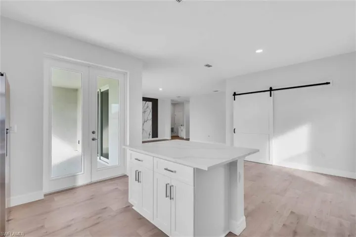Kitchen with a barn door for the pantry, white cabinets, recessed lighting, light wood-style floors, and a kitchen island