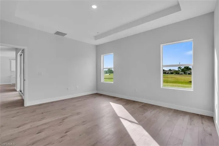 Primary bedroom with trey ceiling, light wood-style floors, and recessed lighting