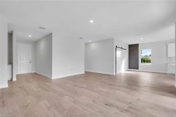 Unfurnished living/dining room with a barn door to the pantry