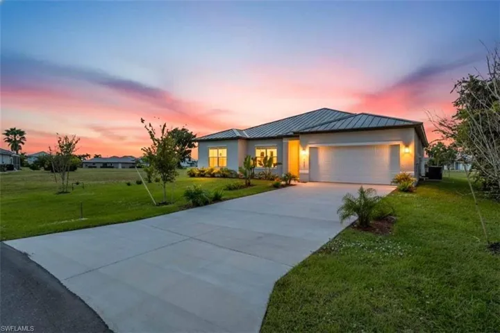 View of front facade with a metal roof, concrete driveway, a front lawn, and a standing seam roof