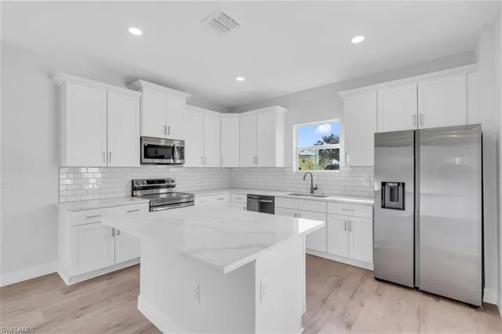 Kitchen with appliances with stainless steel finishes, white cabinetry, decorative backsplash, and recessed lighting