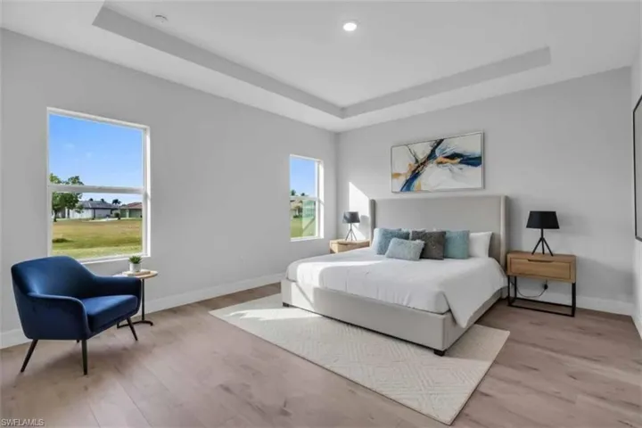 Virtually staged primary bedroom with trey ceiling and light wood-style floors