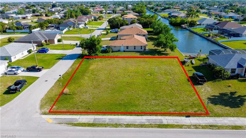 Aerial view of residential area featuring property parcel outlined and a nearby body of water