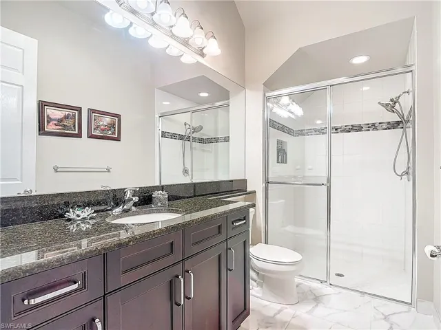 Bathroom featuring vanity, toilet, and walk in shower