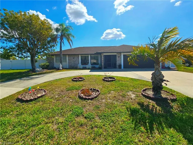 Single story home featuring a garage, fence, a front lawn, and curved driveway