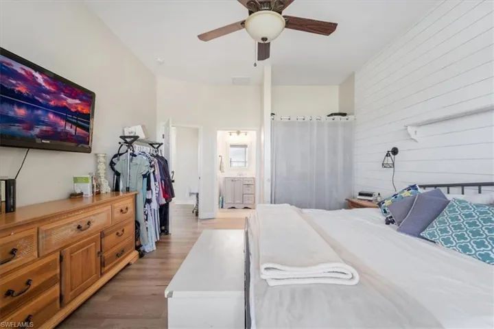 Bedroom featuring ensuite bath, light wood-type flooring, and a ceiling fan