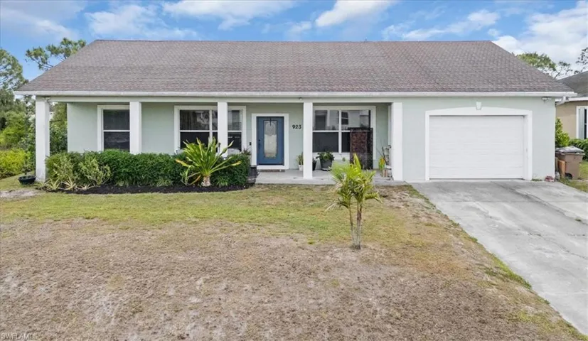 Ranch-style home featuring concrete driveway, stucco siding, an attached garage, a front lawn, and a shingled roof